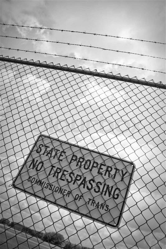 A no trespassing sign that reads STATE PROPERTY NO TRESPASSING outside an airport, stock photo