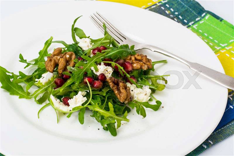 Salad with arugula, pomegranate seeds, feta and walnuts. Studio Photo, stock photo