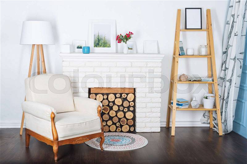 Modern light interior with fireplace and cozy white armchair, stock photo