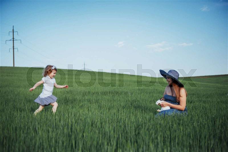 Happy family with two people hugging in the streets. The mother awaiting child. The smiling faces of women and children. Children playing with her mother, stock photo