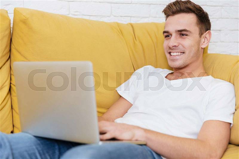 Man sitting on sofa with laptop in office. Coworking, stock photo
