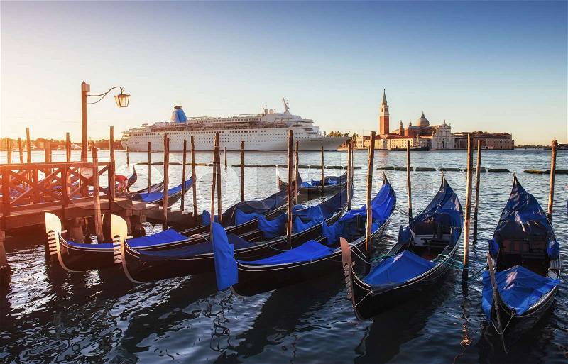 Gondolas on the huge luxury cruise ship in the Grand Canal in Venice. More than 10 million tourists visit Venice every year. People argue that the environmental impact of large cruise ships of the old town is unstable for fragile city. Italy, stock photo