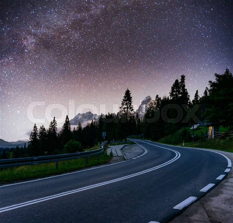 Starry Sky over the mountains. The asphalt road with white markings. Beautiful summer landscape. Soft filtering effect. Carpathians. Ukraine. Europe, stock photo