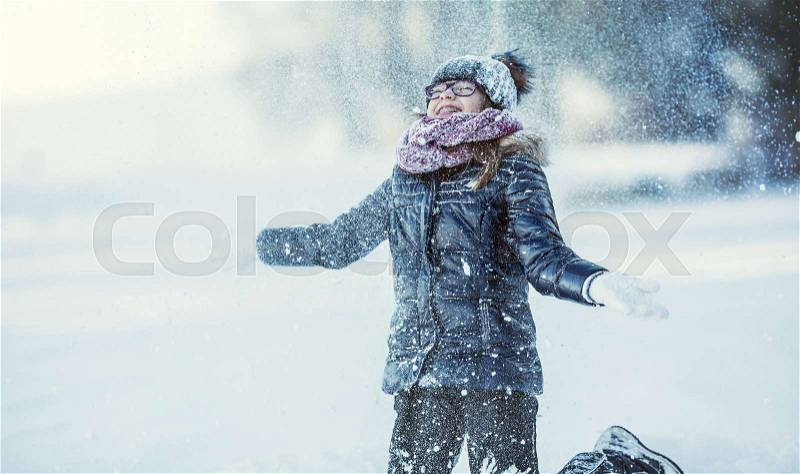 Young girl are playing with snow.Beauty Winter happy Girl Blowing Snow in frosty winter park or outdoors. Girl and winter cold weather, stock photo