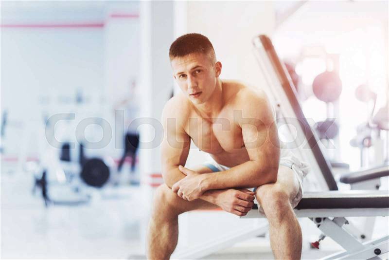 Portrait of a beautiful and attractive young man with muscular body relaxing in the gym, showing strong chest, stock photo