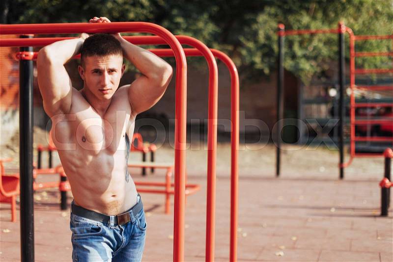 Strong young athlete engaged on the playground. Exercises on the bars outdoors. Fitness. Sport. Exercises, stock photo