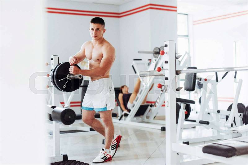 Beautiful man with big muscles, posing for the camera in a nice bright room gym. Sport. Fitness, stock photo