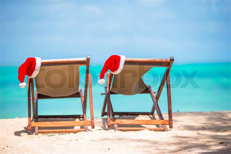 Christmas on the beach -chair lounges with Santa hats at sea. Christmas vacation concept, stock photo