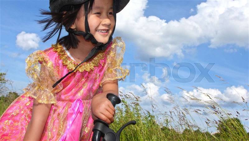 Cute girl cycling with a princess outfit in denmark, stock photo