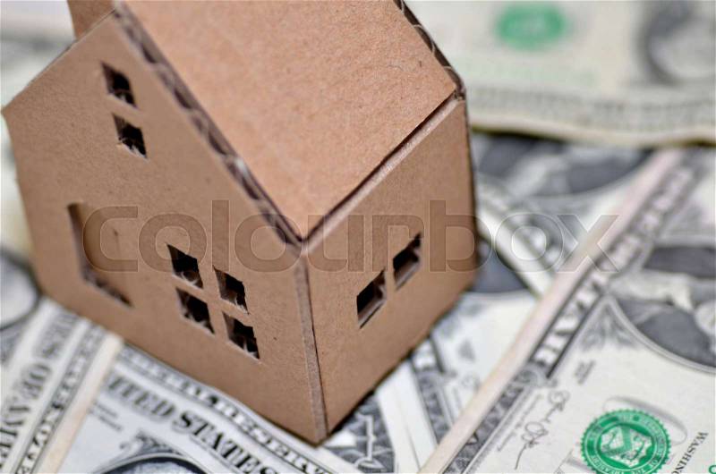 Miniature paper made house stand on money, stock photo