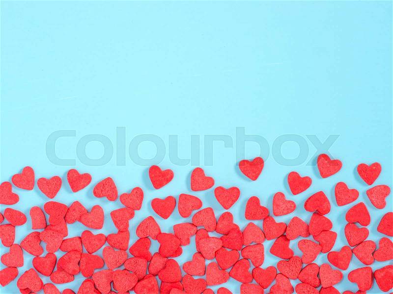Border frame of red hearth-shape sprinkles on blue background with copyspace. Top view or flat lay, stock photo