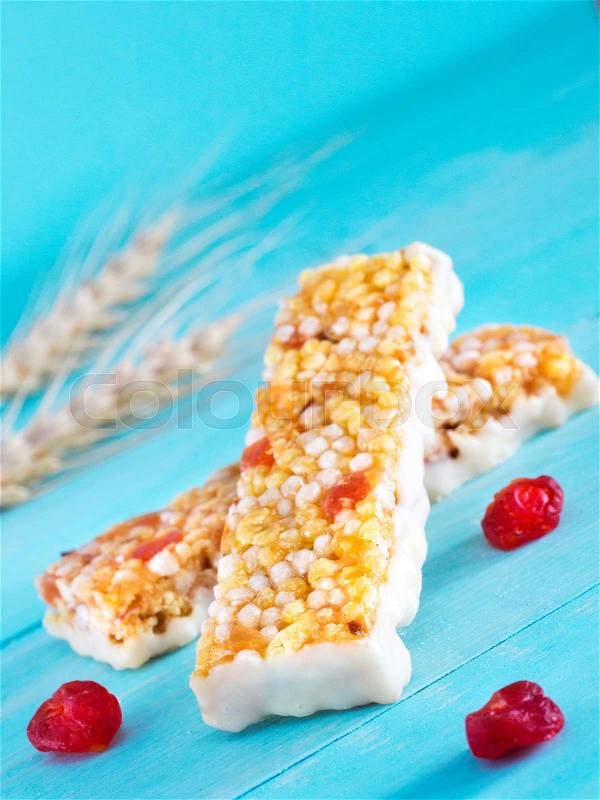 Muesli bar with white chocolate on cerulean blue background. Selective focus. Copy space. Vertical, stock photo