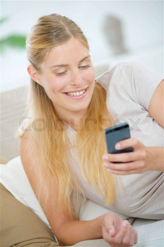 Lady at home looking at cellphone, stock photo