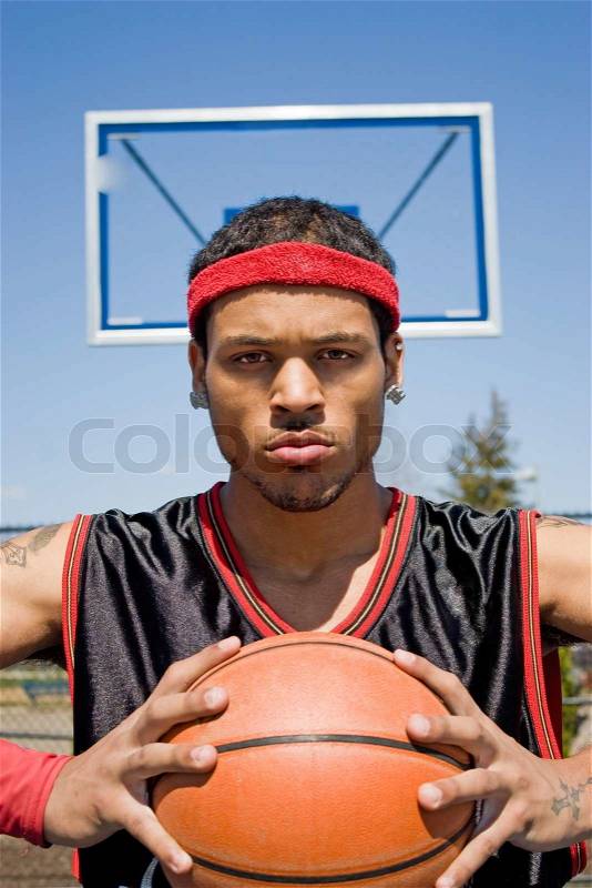 A young basketball player gripping the ball tightly, stock photo