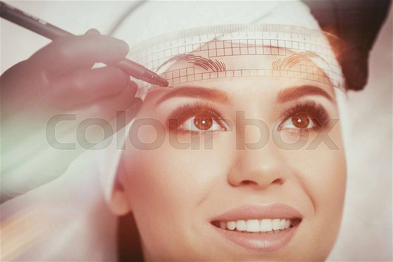 Permanent makeup eyebrows. Mikrobleyding eyebrows workflow in a beauty salon. Cosmetologist applying a special permanent makeup on a woman\'s eyebrows, stock photo