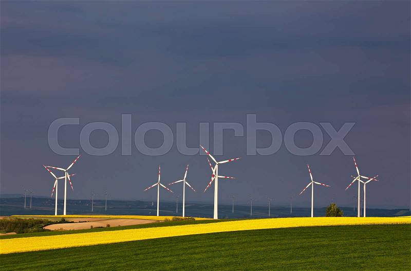 Green and yellow fields with Wind turbines generating electricity. Wind turbines before the thunderstorm. Spring sunny day on green field with wind power generators in Austria, stock photo