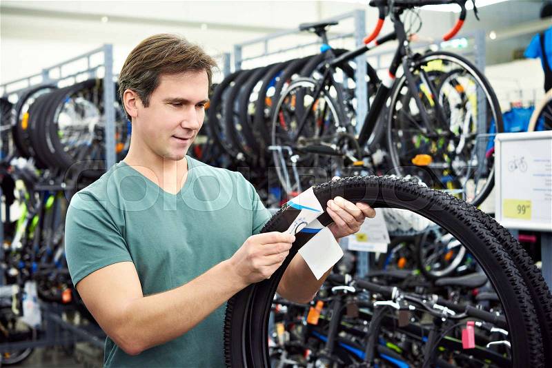 Man chooses the tire to the bike in the sports shop, stock photo