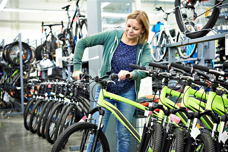 Attractive woman testing the bike in the store, stock photo