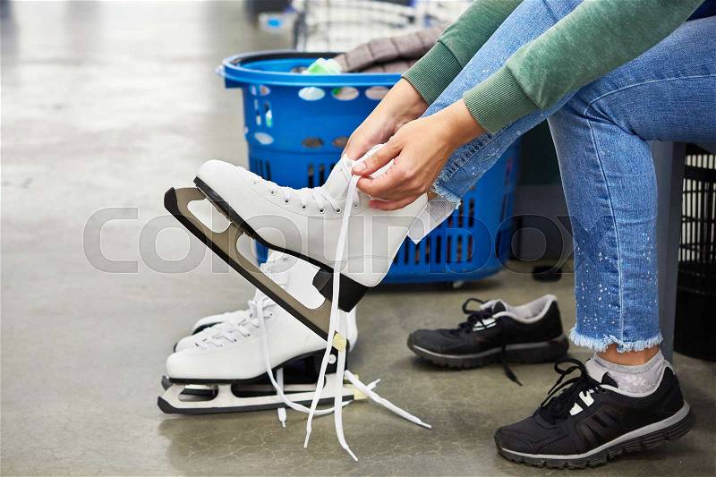 Woman laces figure skates in the sports shop, stock photo