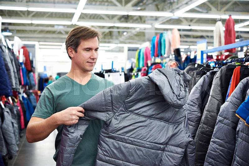 Man chooses a winter jacket in the store, stock photo