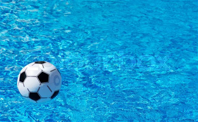 Beach ball floating in blue swimming pool. Space for text, stock photo