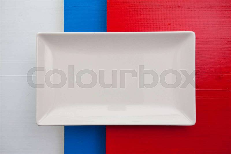 Empty white ceramic dish on over white,blue and red wooden table, rectangle dish, stock photo