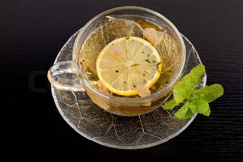 Cup of green tea with lemon and mint on dark wood table, stock photo