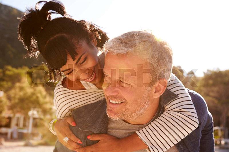 Happy middle aged couple piggybacking on the beach, Ibiza, stock photo