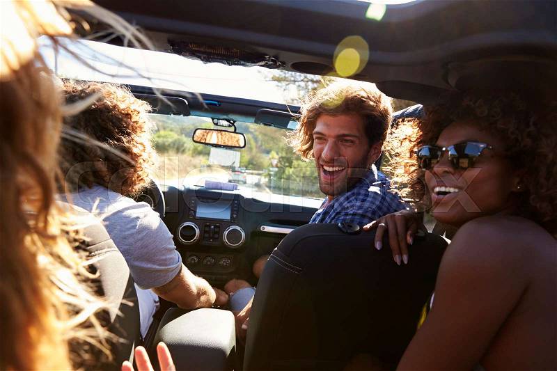 Four friends driving in an open top car, rear passenger POV, stock photo