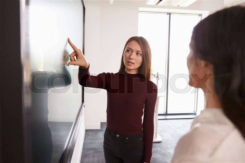 Student And Tutor Discuss Project On Interactive Whiteboard, stock photo