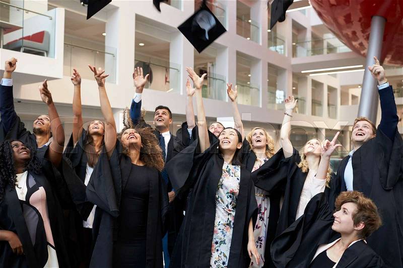 University students throwing their caps in the air on graduation day, stock photo
