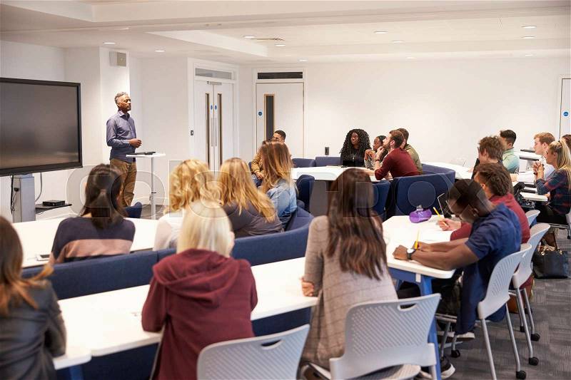 University students study in a classroom with male lecturer, stock photo