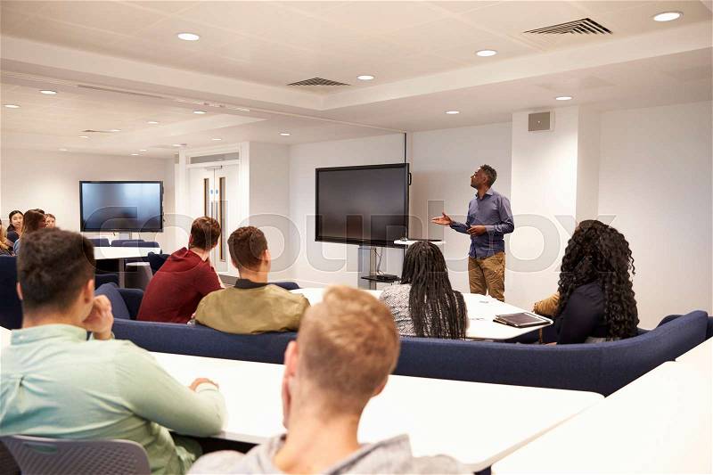 University students study in a classroom with male lecturer, stock photo