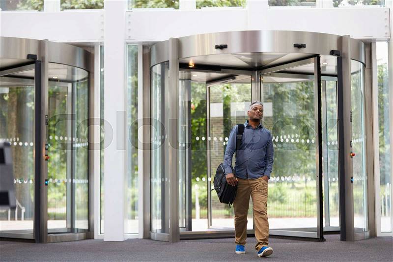 Middle aged black man entering the foyer of modern building, stock photo