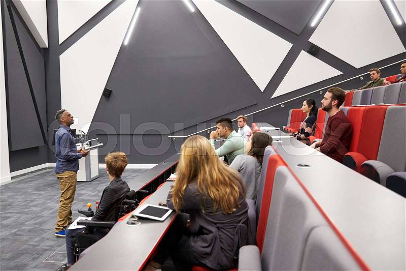 Man lectures students in lecture theatre, front row seat POV, stock photo