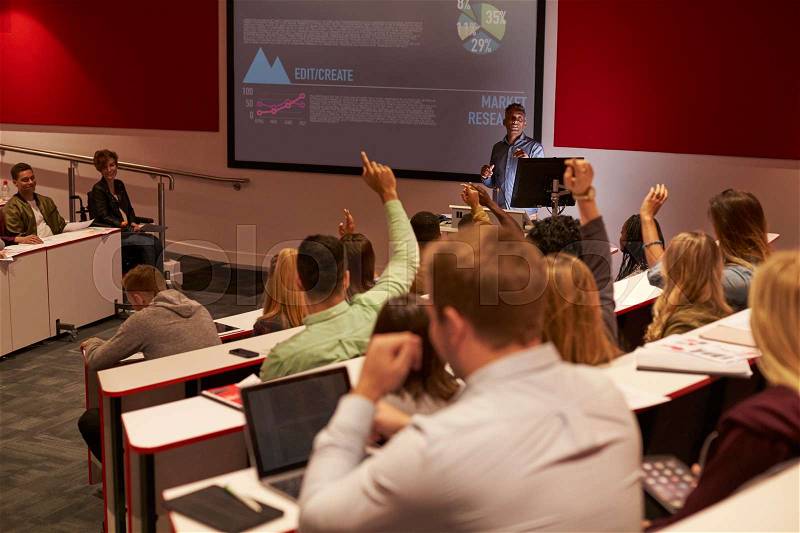 Students at university lecture raise hands to ask questions, stock photo