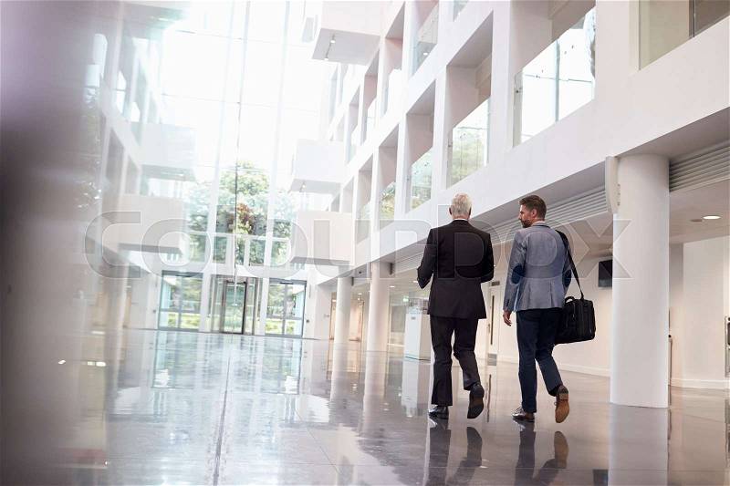 Rear View Of Businessmen Walking Through Office Lobby, stock photo