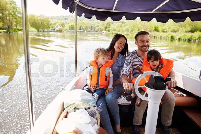 Family Enjoying Day Out In Boat On River Together, stock photo