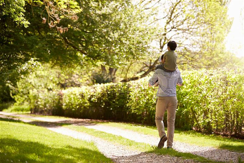 Rear View Of Father Giving Son Ride On Shoulders During Walk, stock photo