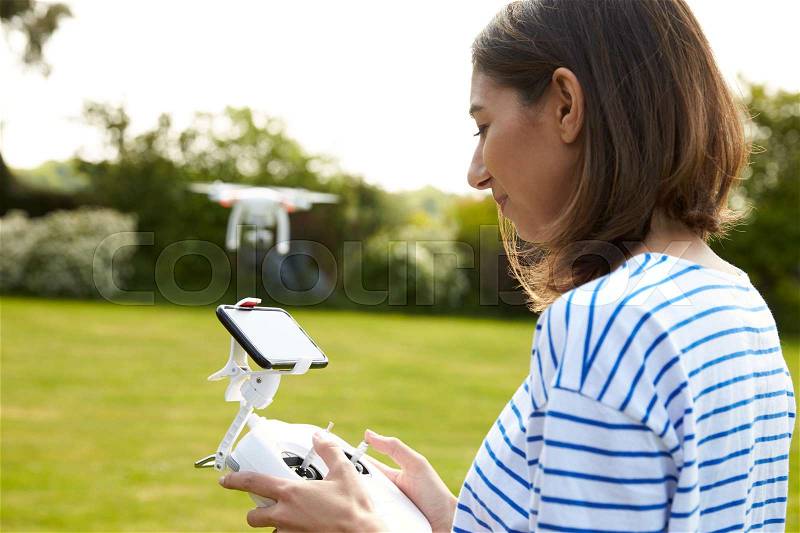 Woman Flying Drone Quadcopter In Garden, stock photo