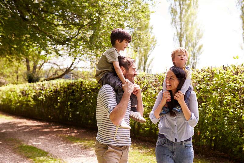 Parents Giving Sons Ride On Shoulders During Walk, stock photo