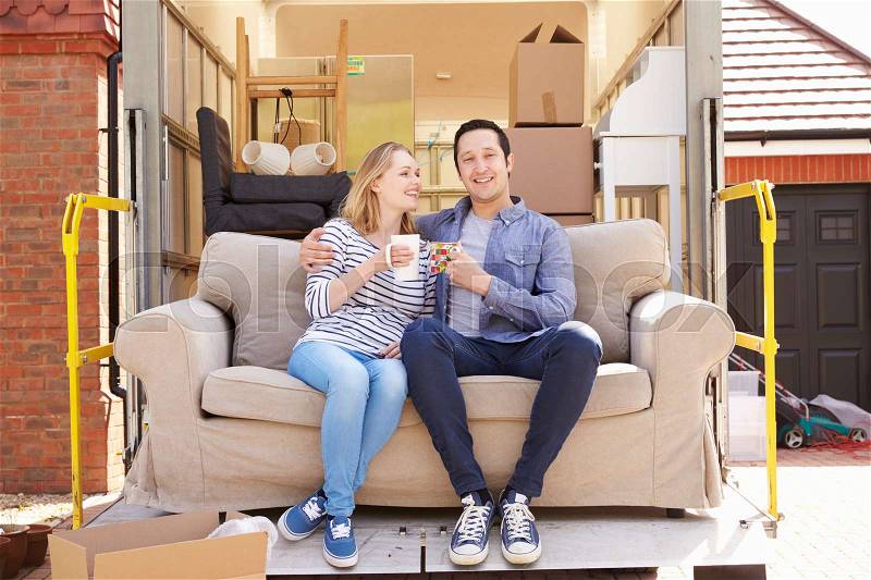 Couple With Sofa On Tail Lift Of Removal Truck Moving Home, stock photo