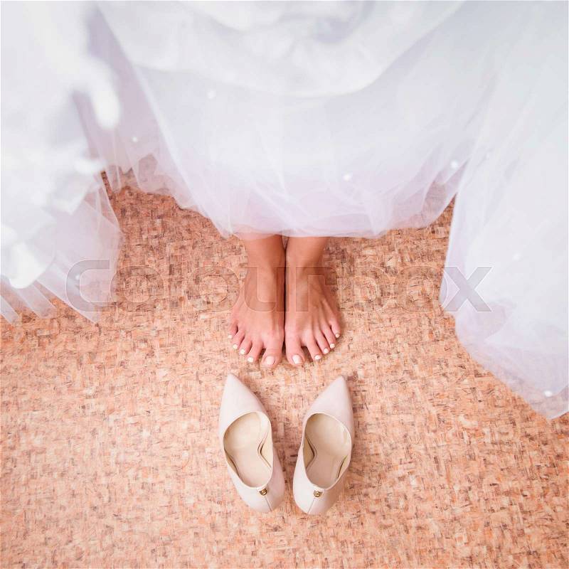 Bride's feet in shoes under wedding dress, stock photo