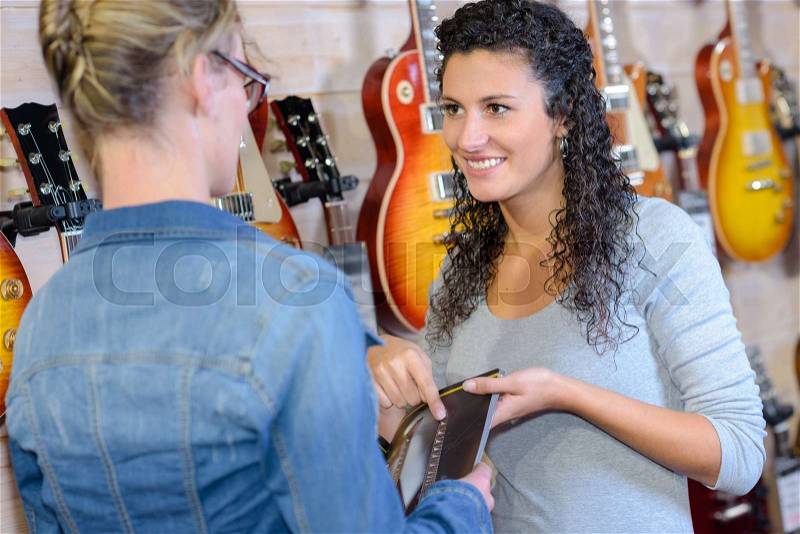 Sales clerk advising customer in musical instrument shop, stock photo