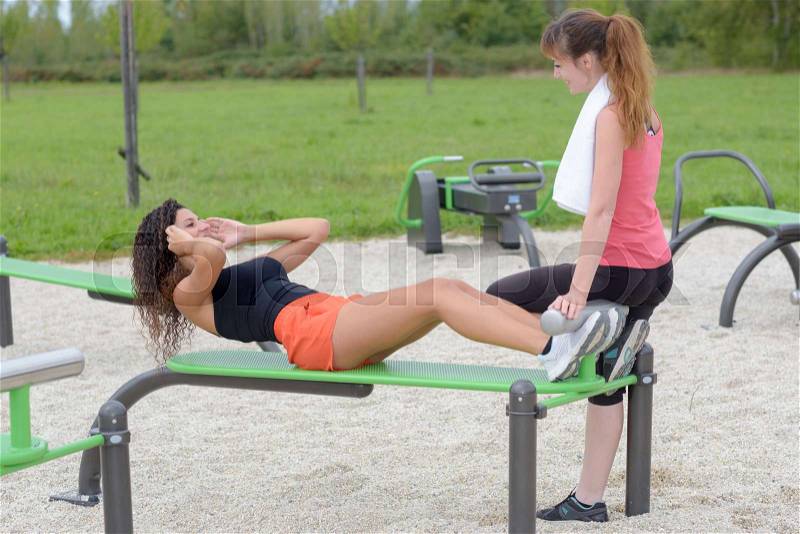 Lady holding feet of friend doing situps, stock photo