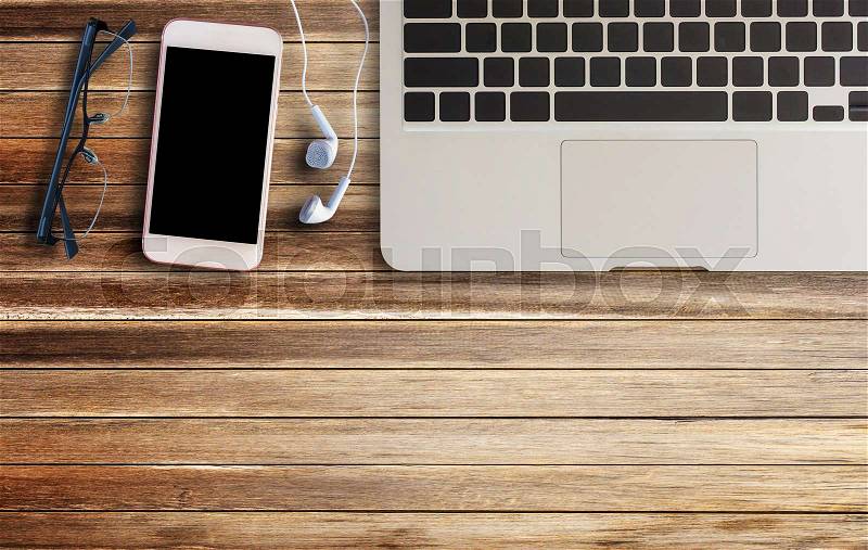 Laptop computer,glasses,earphone and smart phone on brown old wood background and texture with copy space, stock photo