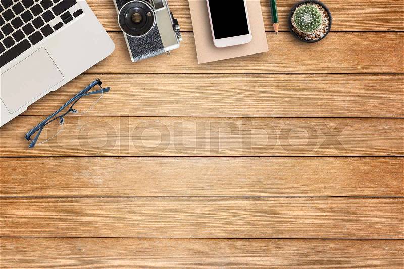 Office desk table with office equipment,laptop computer, glasses, smart phone camera and flower on wooden table background. Top view with copy space (selective focus), stock photo