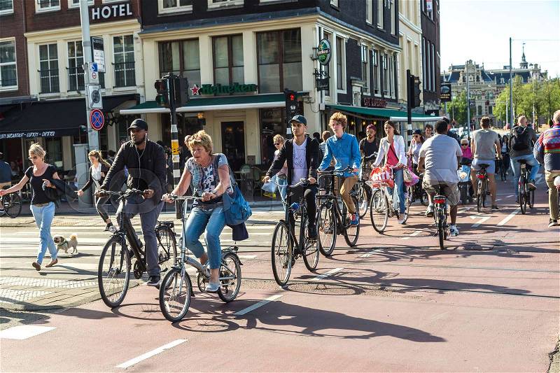 AMSTERDAM, THE NETHERLANDS - JUNE 16, 2016: People riding bicycles in historical part of Amsterdam in a beautiful summer day, The Netherlands on June 16, 2016, stock photo