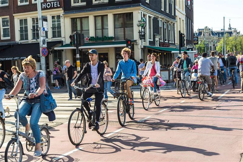 AMSTERDAM, THE NETHERLANDS - JUNE 16, 2016: People riding bicycles in historical part of Amsterdam in a beautiful summer day, The Netherlands on June 16, 2016, stock photo