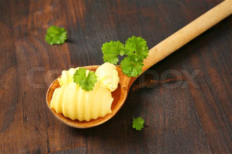 Butter curls and fresh parsley on wooden spoon, stock photo